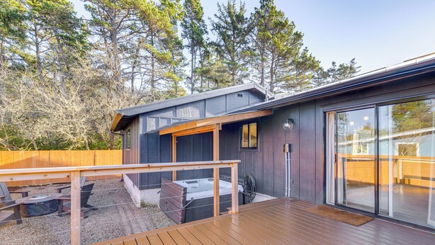 A modern outdoor deck with a hot tub, wooden deck, and a glass-enclosed patio area. - Modern Oregon Cottage w/ Hot Tub: Walk to Beach! (Cloverdale)