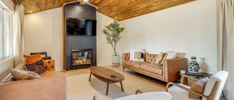 Una sala de estar acogedora con chimenea, techo de madera y asientos cómodos.