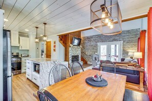 A spacious kitchen with white cabinets, a large island, and a stone fireplace. - Hot Tub & Movie Room: Updated Cabin in Ellijay! (Ellijay)