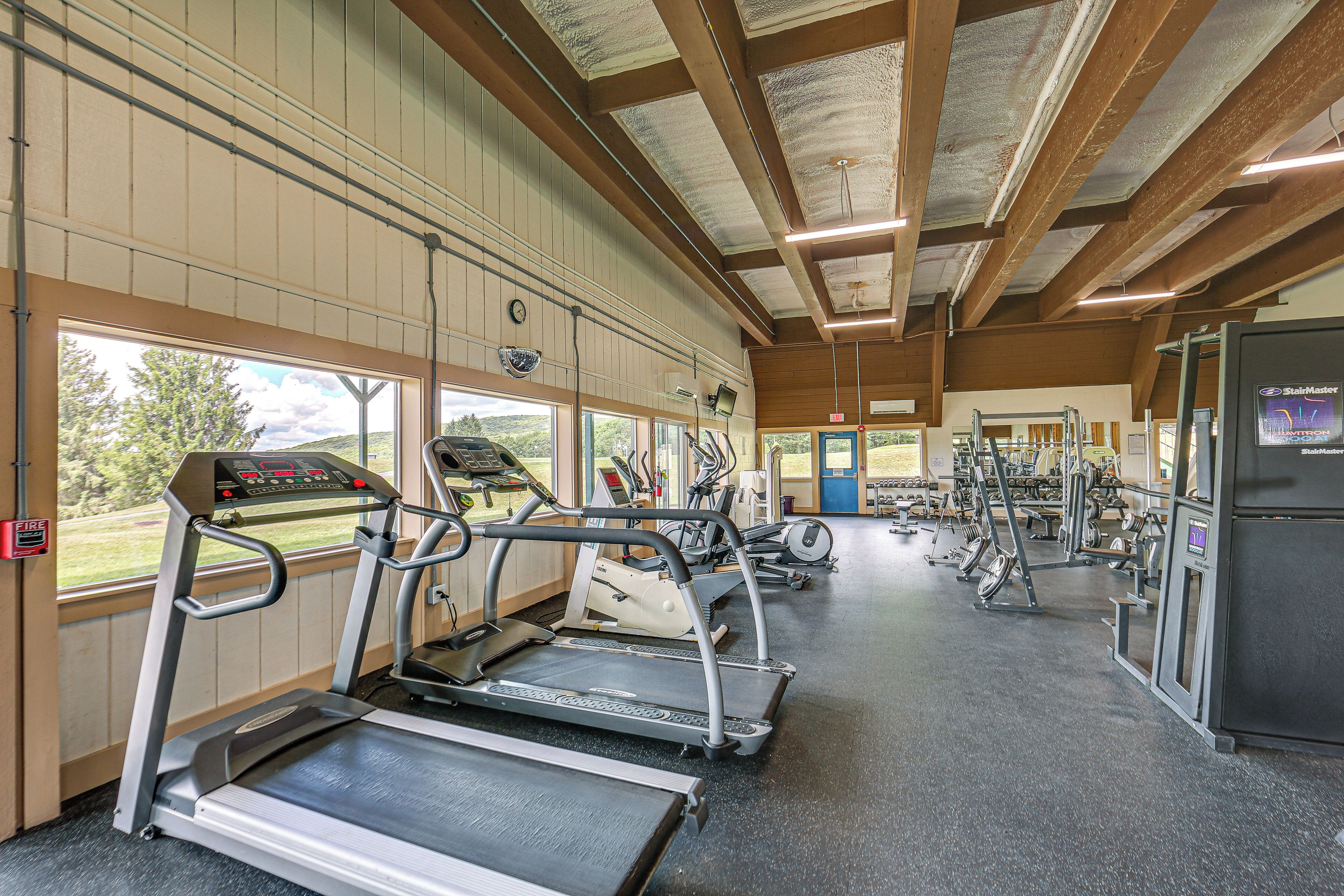 Une salle de sport équipée de tapis de course, d’appareils de musculation et d’une grande fenêtre donnant sur l’extérieur.