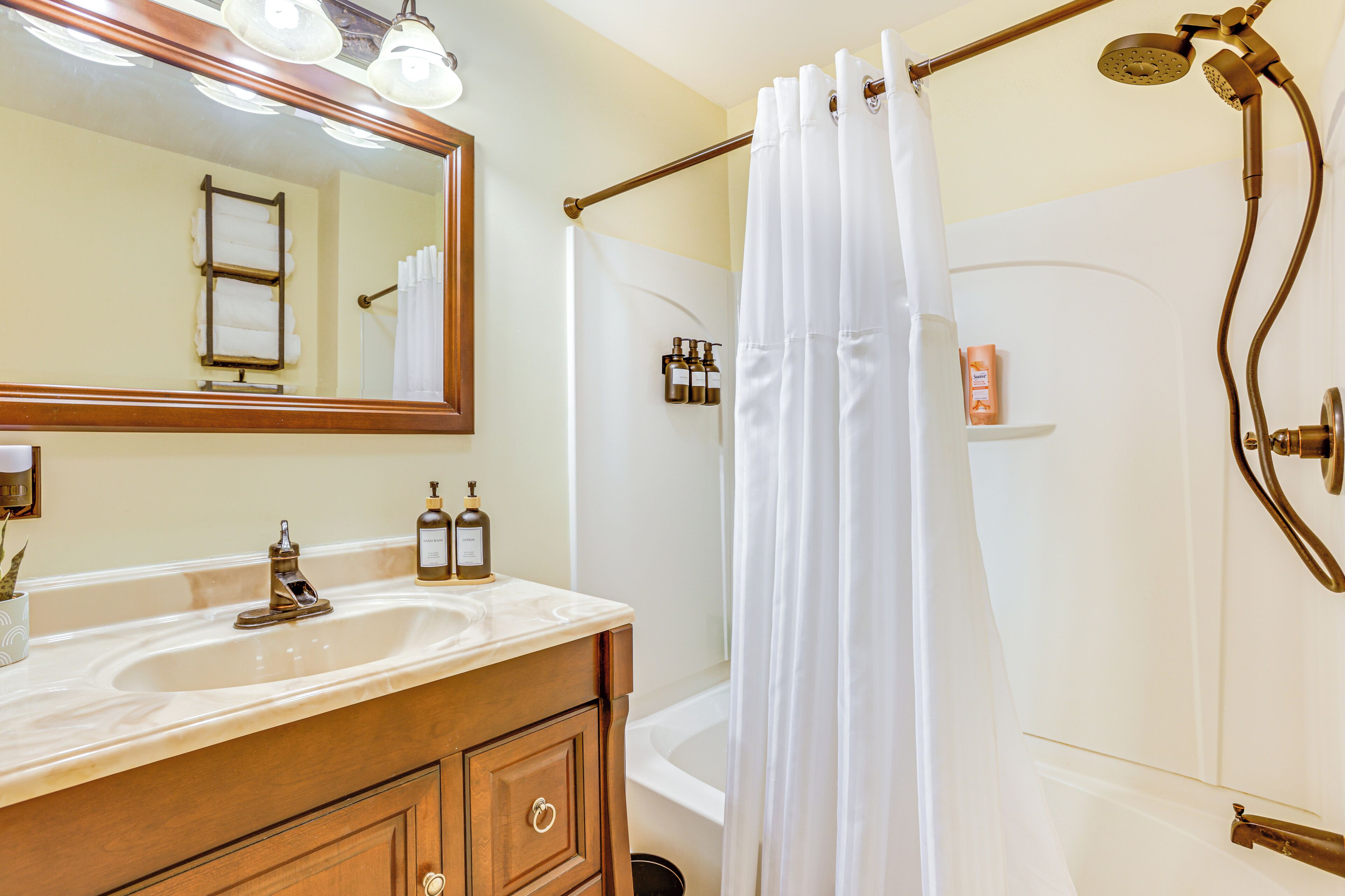 A bathroom with a double sink vanity, a large mirror, a shower with a curtain, and a bathtub.