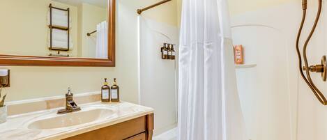 A bathroom with a double sink vanity, a large mirror, a shower with a curtain, and a bathtub.