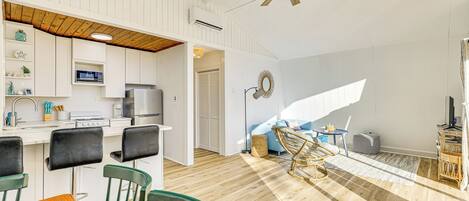 A modern kitchen with white cabinets, a wooden ceiling fan, and a dining area with a wooden table and chairs.