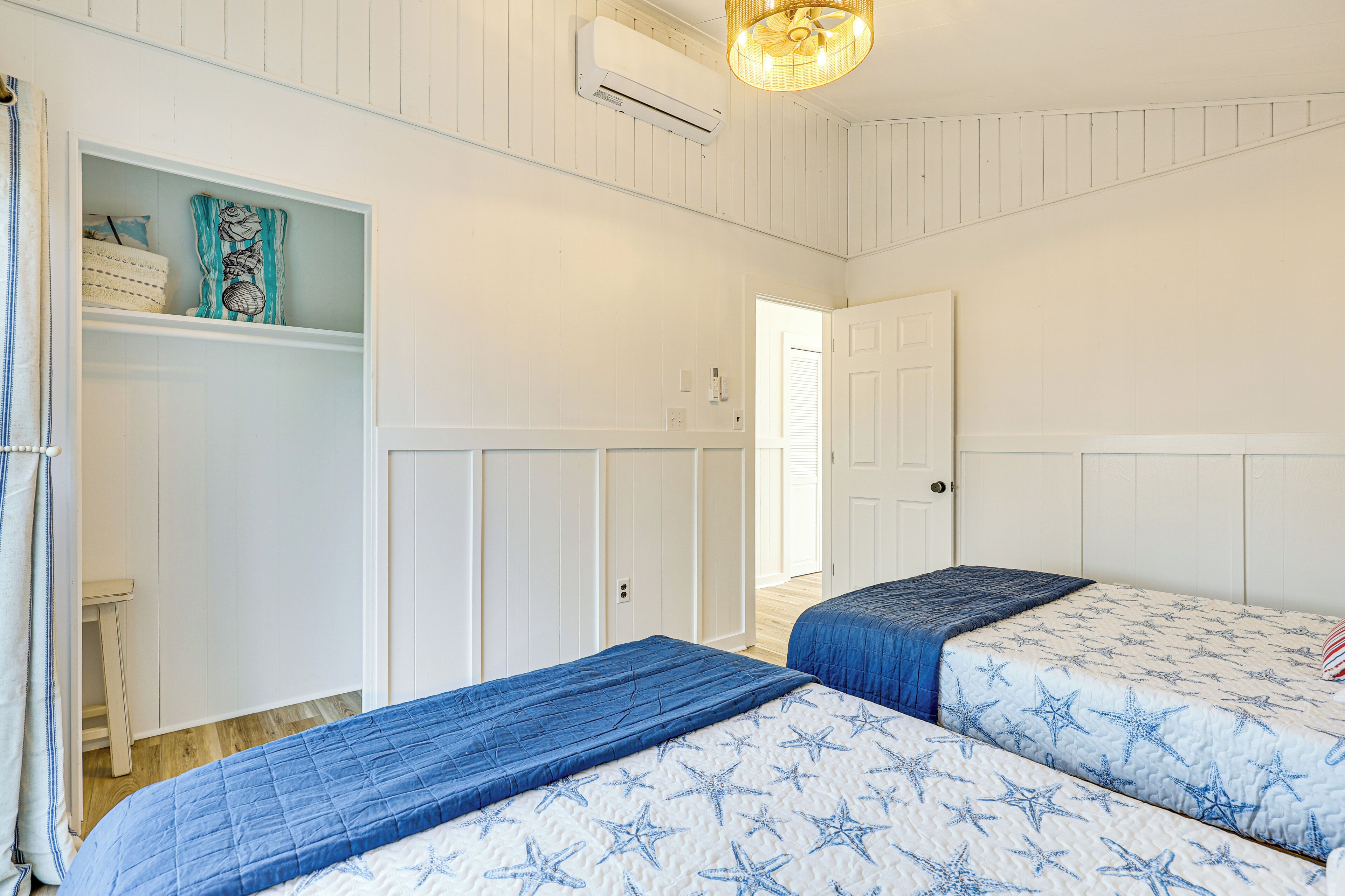 Un dormitorio con dos camas, un armario y una puerta que da a otra habitación.