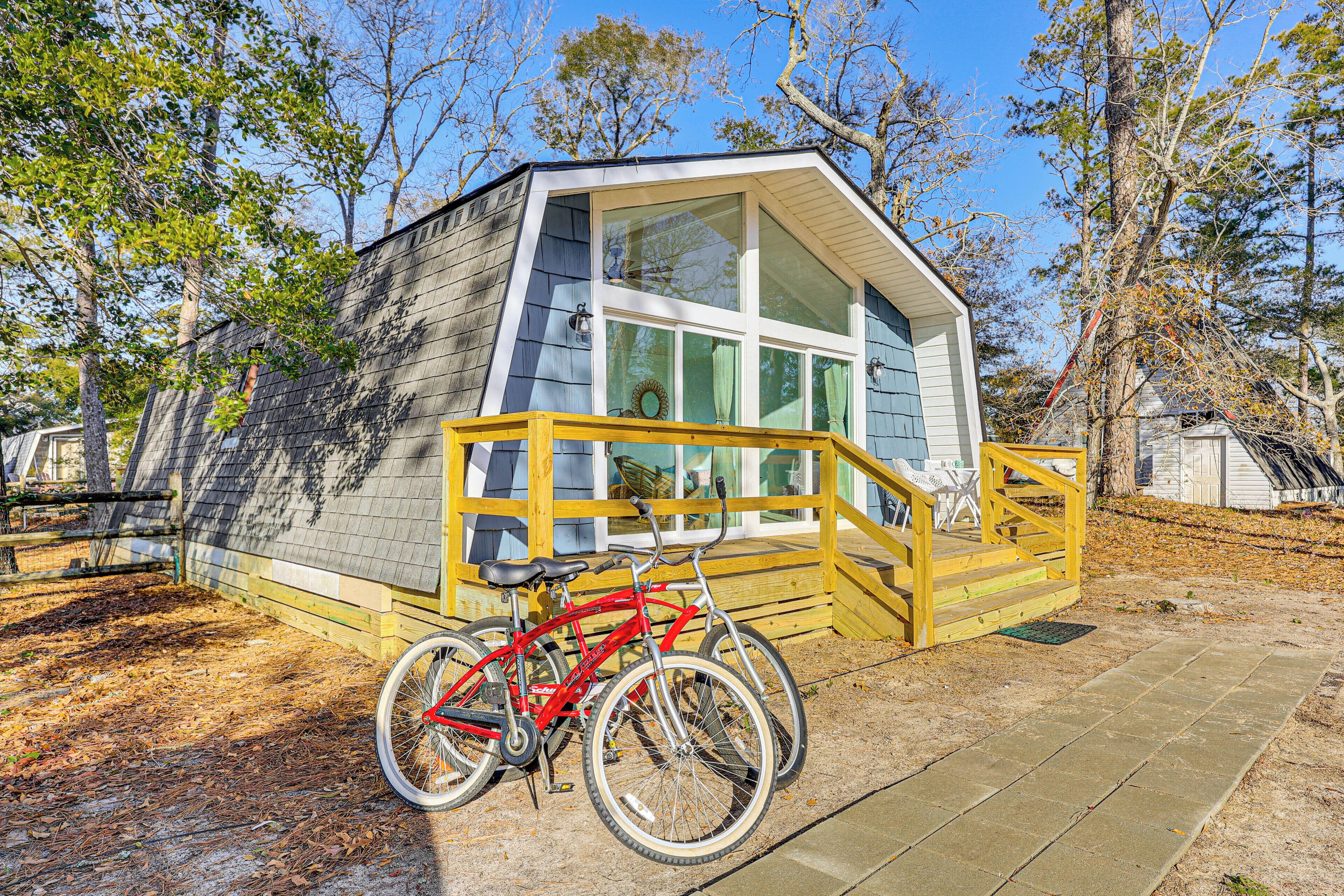 A small cabin with a wooden deck and a bicycle parked in front.