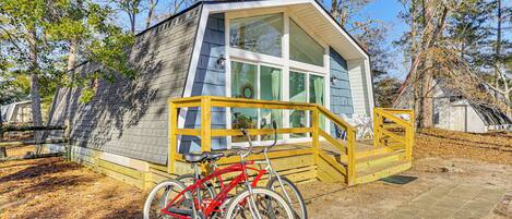 A small cabin with a wooden deck and a bicycle parked in front.