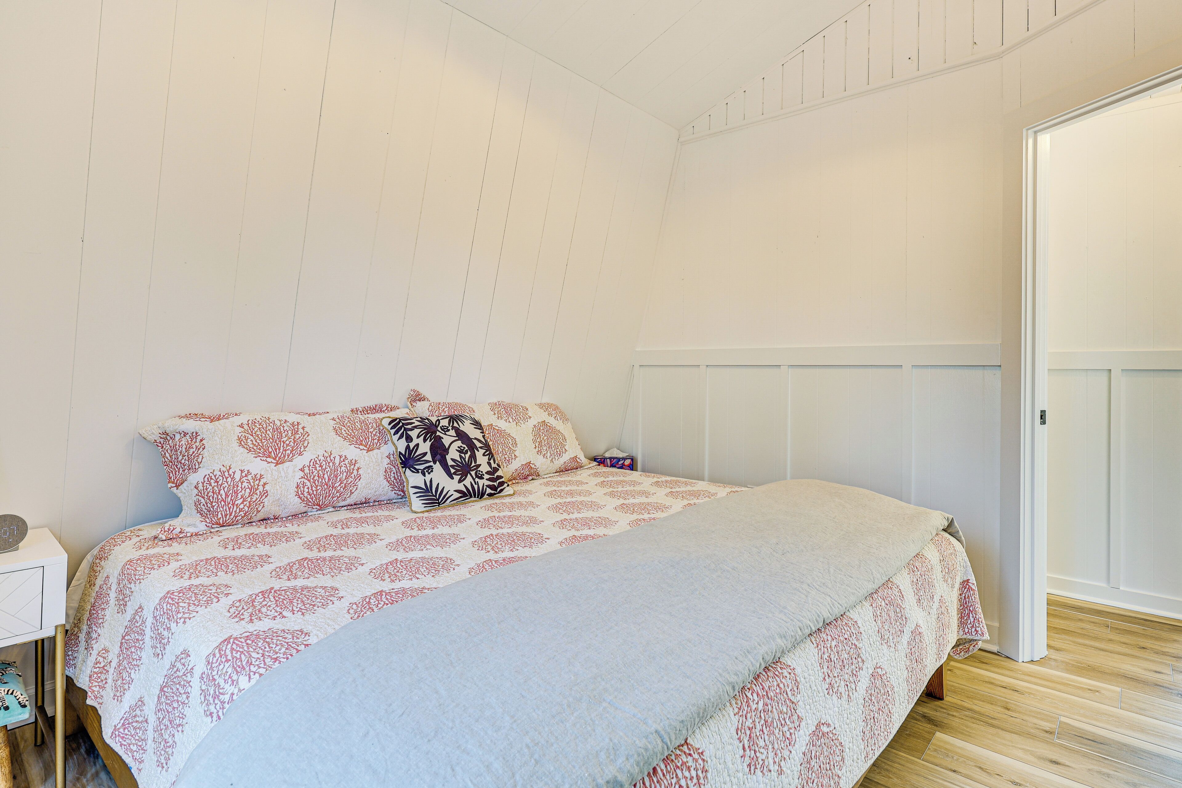 A bedroom with a bed, a nightstand, and a door.