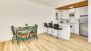 Et moderne køkken med hvide skabe, træloft og en central ø med barstole.