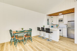 Una cocina moderna con armarios blancos, techo de madera y una isla central con taburetes de bar.