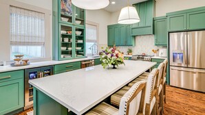 Une cuisine moderne avec des meubles verts, un plan de travail en marbre et des appareils électroménagers en acier inoxydable.