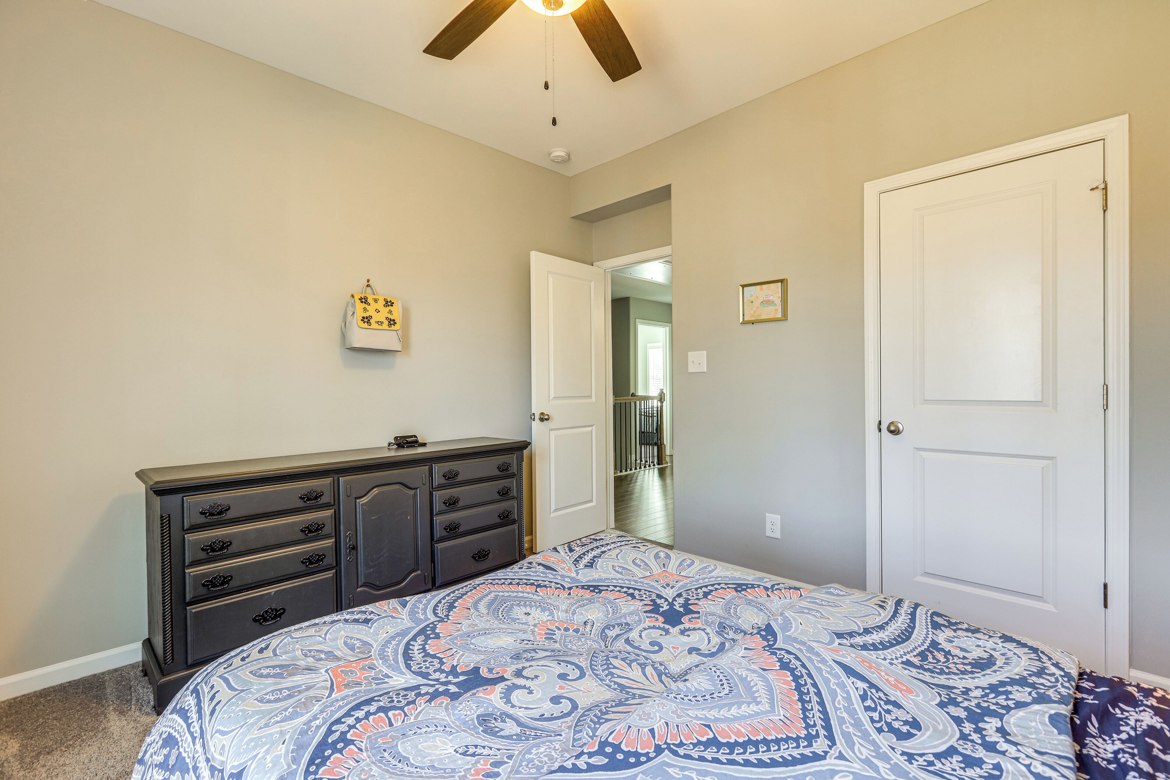 A bedroom with a bed, dresser, and two doors.