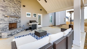 An outdoor patio with a stone fireplace, wicker furniture, and a ceiling fan. - Patio w/ Fireplace: Spacious Sharpsburg Home! (Sharpsburg)