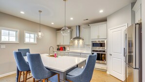 A modern kitchen with a central island, bar stools, stainless steel appliances, and pendant lighting. - Patio w/ Fireplace: Spacious Sharpsburg Home! (Sharpsburg)