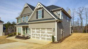A two-story house with a garage, a front porch, and a well-maintained lawn. - Patio w/ Fireplace: Spacious Sharpsburg Home! (Sharpsburg)
