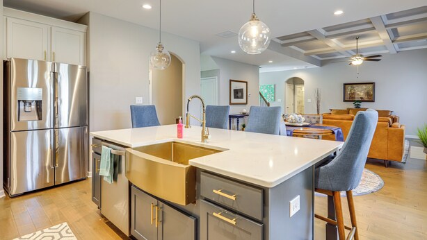 A modern kitchen with a stainless steel refrigerator, a double sink, and a large island with bar stools. - Patio w/ Fireplace: Spacious Sharpsburg Home! (Sharpsburg)