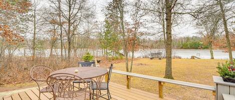 A wooden deck with a table and chairs overlooking a lake.