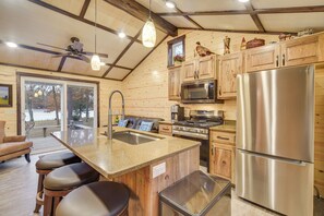 Eine Küche mit Holzausstattung, Edelstahlgeräten, einer Bar und einem Deckenventilator.