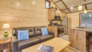 A cozy cabin interior with a wooden interior, a leather sofa, a wooden dining table, and a kitchenette. - Minong Flowage Cabin w/ Fire Pit & Dock! (Gordon)