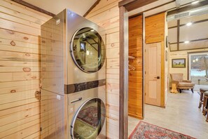 Ein Zimmer mit Holzwänden, einer Waschmaschine und einem großen Spiegel.