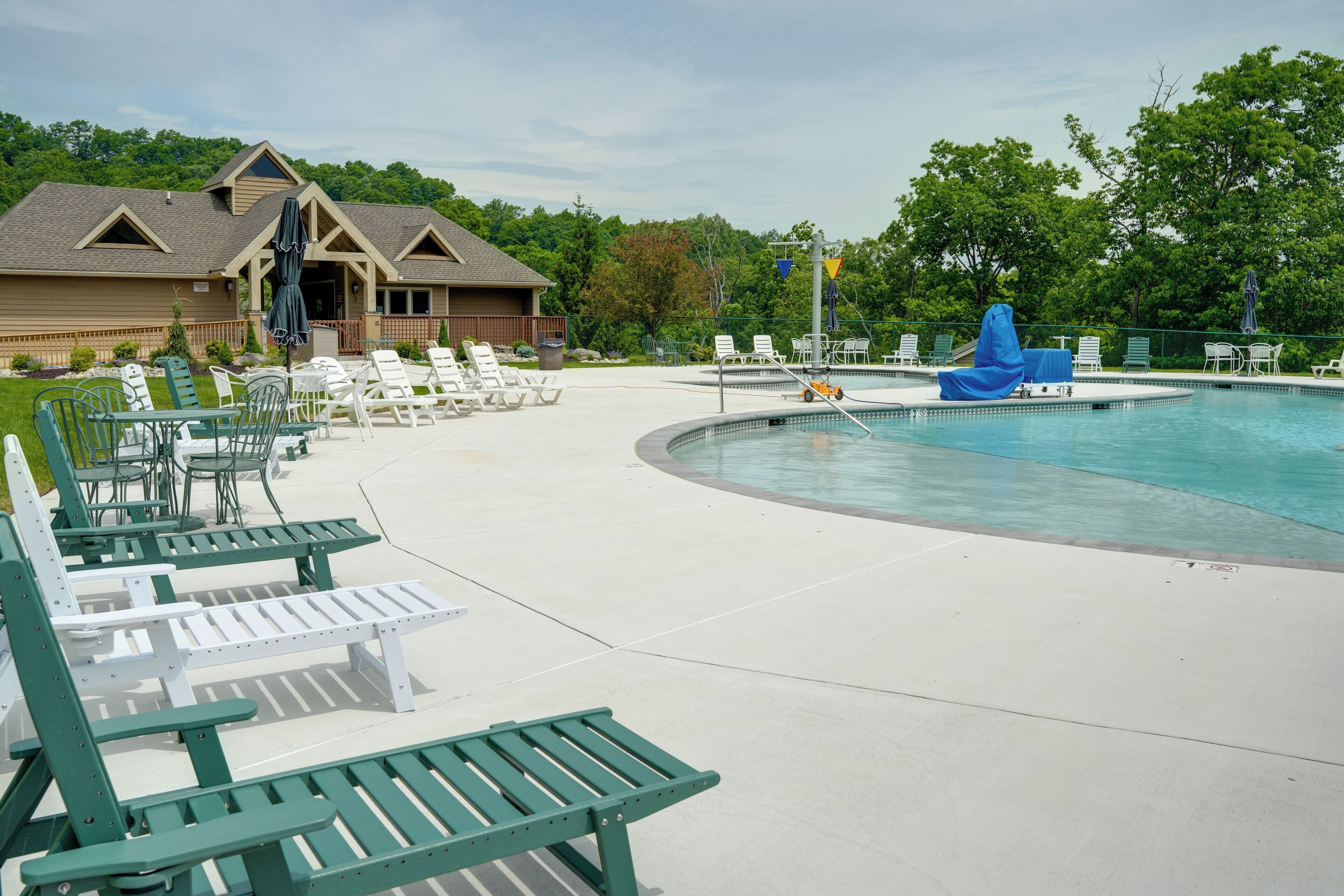 A pool area with lounge chairs, a blue water slide, and a building with a porch.