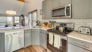 Een moderne keuken met grijze kastjes, roestvrijstalen apparatuur en een groot eiland.