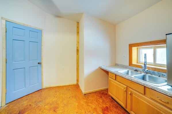 A kitchen with wooden cabinets, a double sink, and a window above the sink.