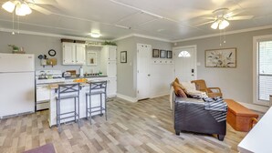 Une cuisine spacieuse avec des meubles blancs, un coin repas doté d’une banquette et un ventilateur de plafond.