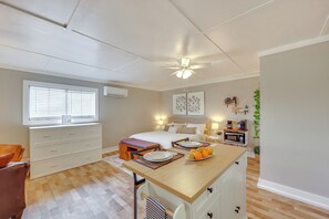 A bedroom with a bed, bedside tables, a desk, a chair, a window, and a ceiling fan.