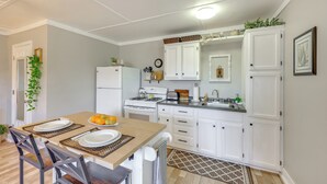 Une cuisine moderne avec des meubles blancs, une table à manger en bois et une cuisinière encastrée.