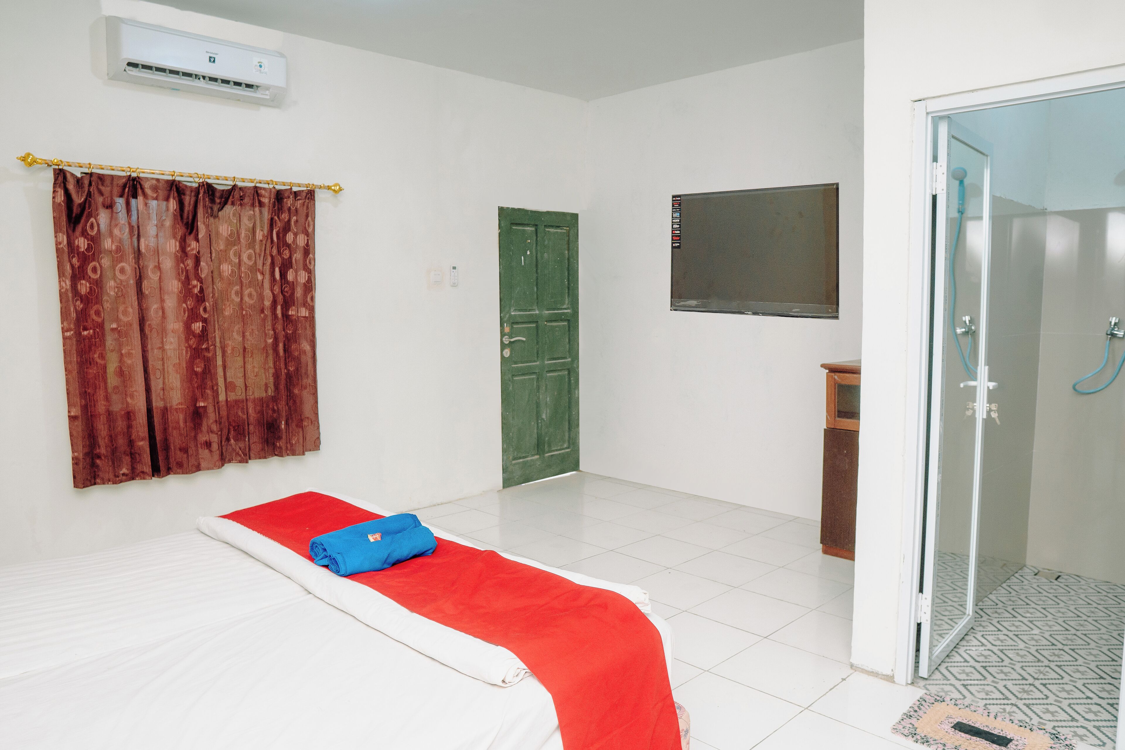 Une chambre avec un lit, une douche et une porte verte.