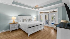 Ein Schlafzimmer mit Bett, Nachttischen, Deckenventilator und Blick durch eine Tür.