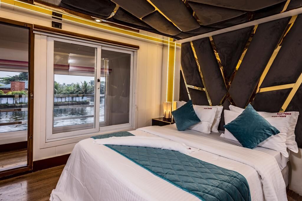 A hotel room with a large bed, a view of a body of water through a sliding door, and a modern headboard design.