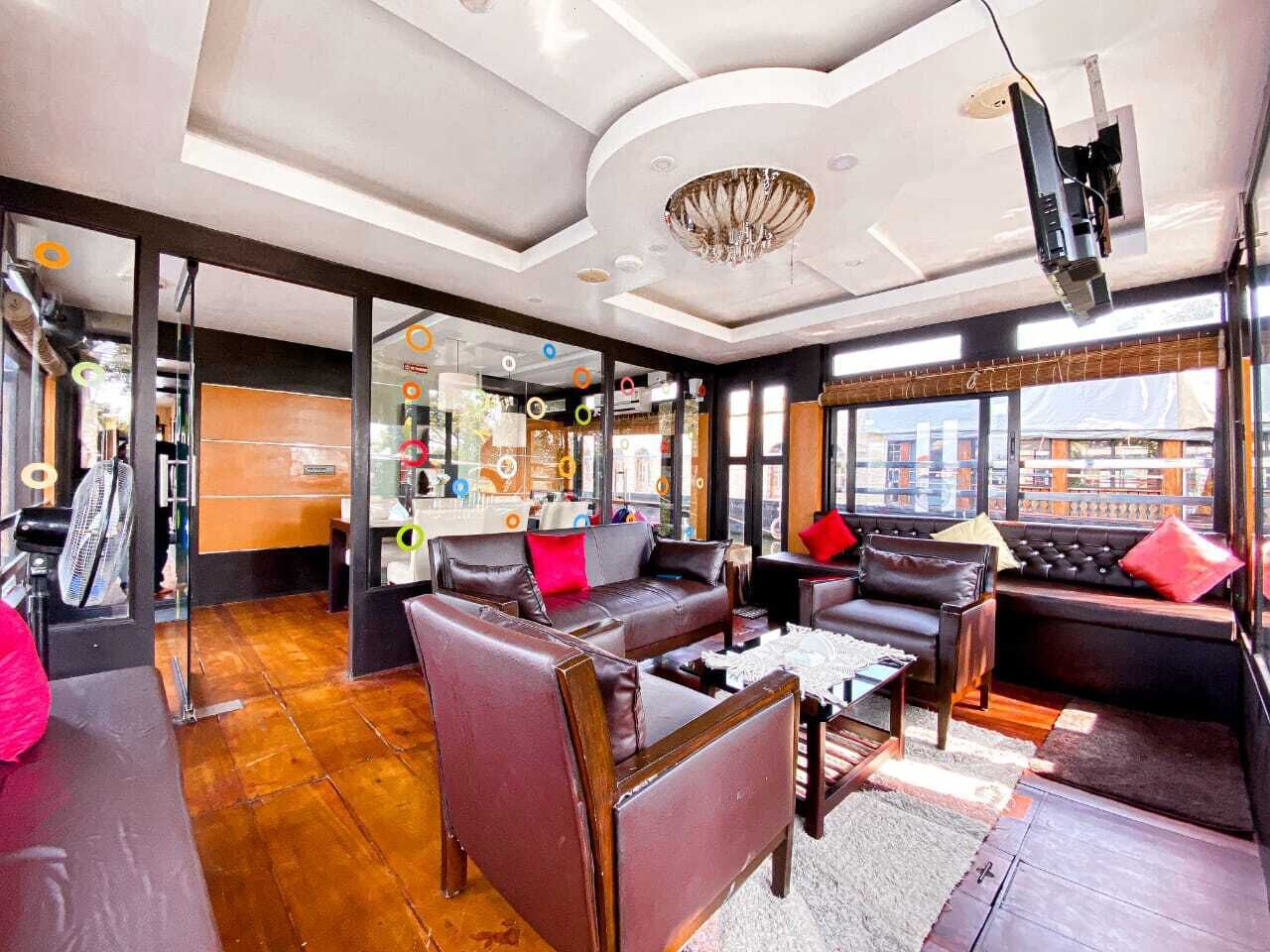 A modern living room with leather sofas, a coffee table, and a large window offering a city view.