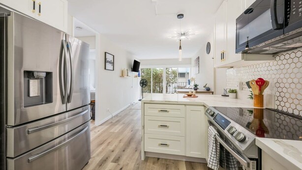 Een moderne keuken met roestvrijstalen apparatuur, een centraal kookeiland met een fornuis en een magnetron boven de aanrecht.