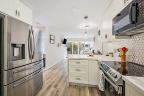 A modern kitchen with stainless steel appliances, a central island with a stove, and a microwave above the counter.
