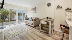 Een moderne woonkamer met een bank, een salontafel, een ventilator en uitzicht door grote glazen deuren.