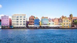 A waterfront with colorful buildings, including a pink building with "The Blue Experience" sign. - Blue Bay s Tropical Escape (Sint Michiel)