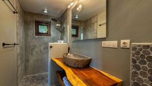 A bathroom with a stone sink, wooden vanity, a mirror, and a shower area. - Blue Bay s Tropical Escape (Sint Michiel)