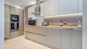 A modern kitchen with stainless steel appliances, a wooden countertop, and integrated lighting. - Rosemount X3 Bed Townehouse With Hot Tub (Windermere)