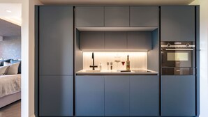 Et moderne køkken med indbyggede apparater, en central ø og et spiseområde med en sofa.
