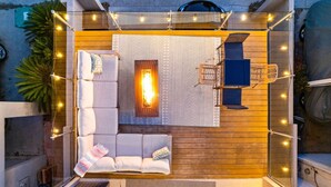 Ein gemütlicher Außenbereich mit einer Couch, einer Feuerstelle und Lichterketten.