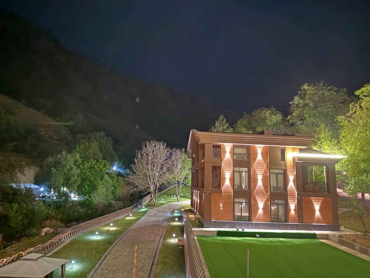 A modern building with a symmetrical facade, surrounded by a well-lit pathway and greenery.