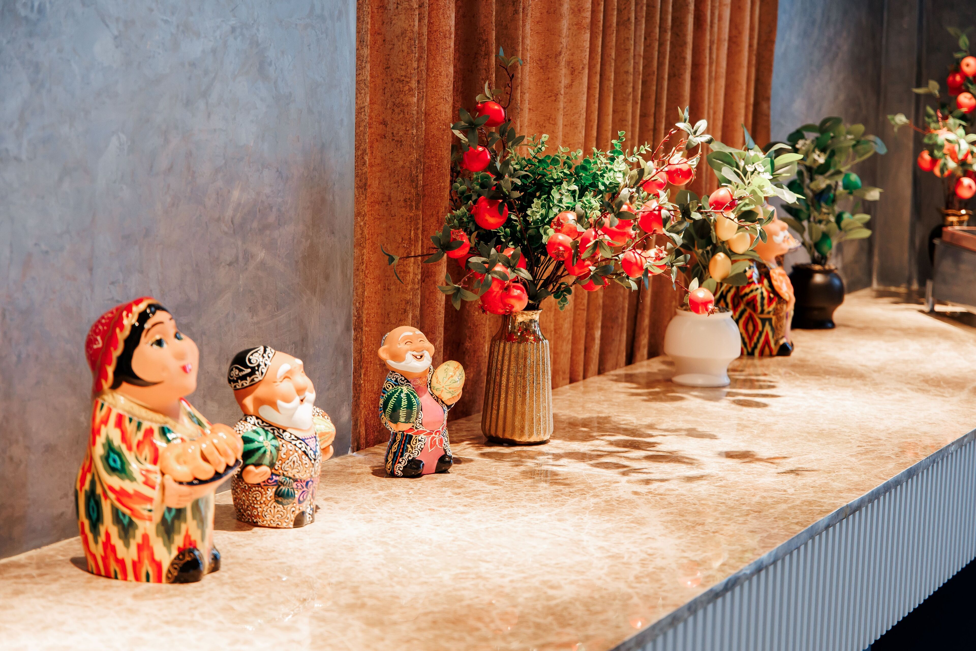 A shelf with decorative figurines and a potted plant with red flowers.