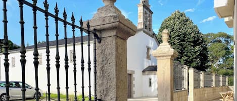 A white building with a stone pillar and a fence.