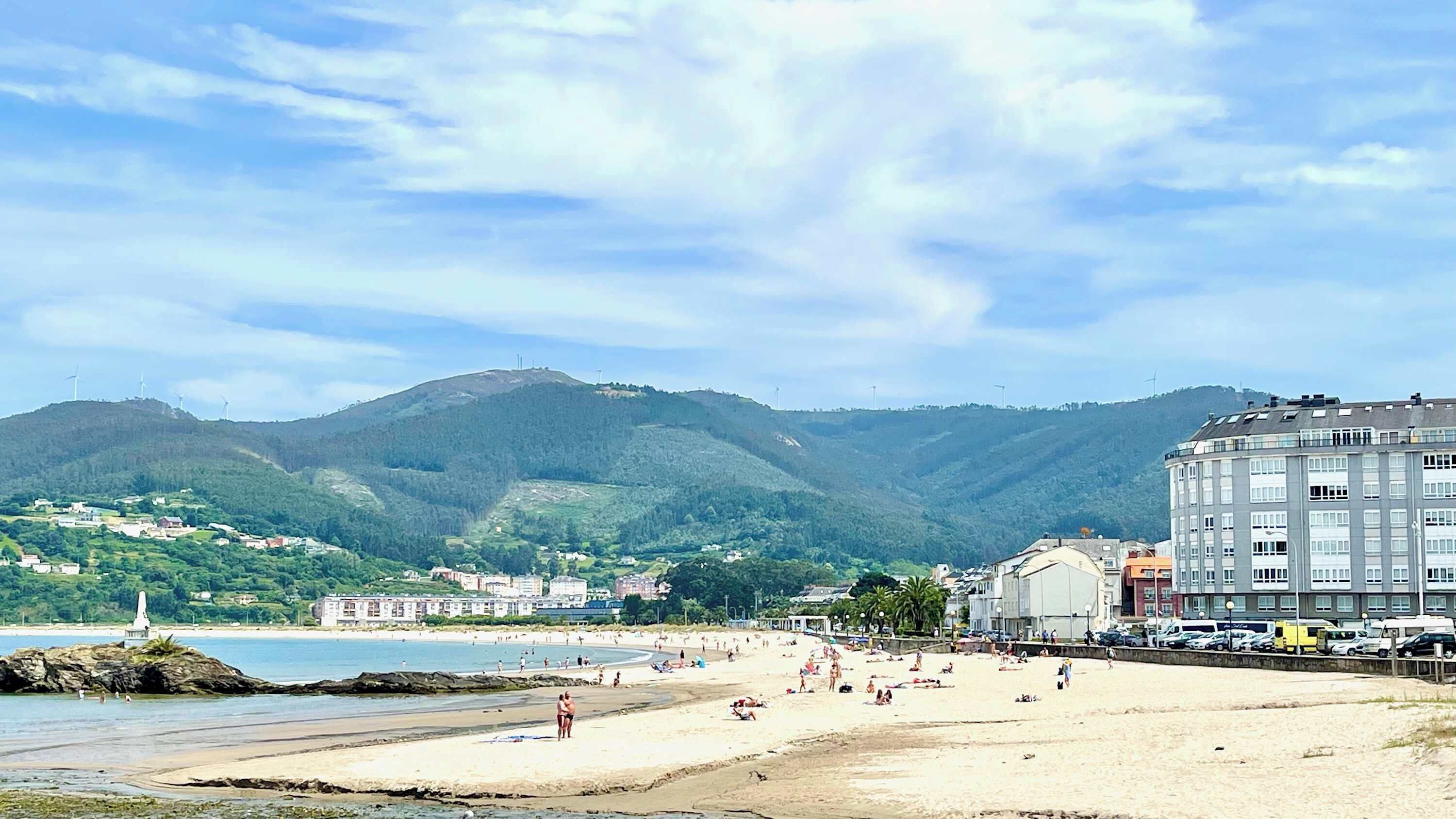 Une plage bordée de montagnes, une rive sablonneuse et un bâtiment à étages.