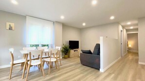 A modern living room with a dining area, a flat-screen TV, and a grey sofa. - The Cliffs - AT Seiramar Portonovo (Viveiro)