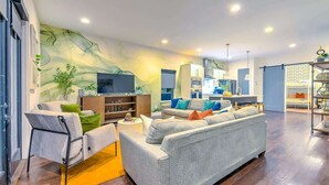 Ein modernes Wohnzimmer mit einem grauen Sofa, einem Fernseher und einem Bücherregal.