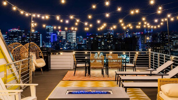 Eine Dachterrasse mit Sitzgelegenheiten, einem Feuerkorb und Blick auf die Stadtlandschaft.
