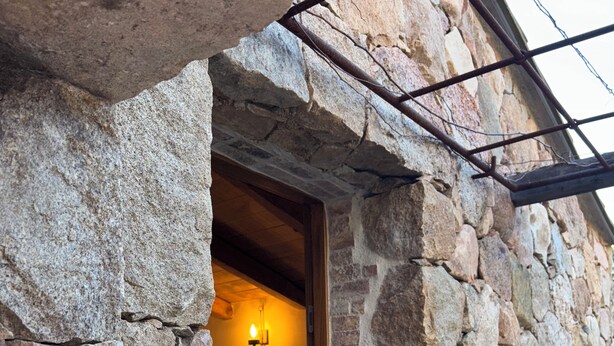 Un bâtiment en pierre doté d’une porte d’entrée qui mène à un espace intérieur.