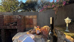 Une table dressée à l’extérieur, avec une bouteille, des verres et un panier de pain.